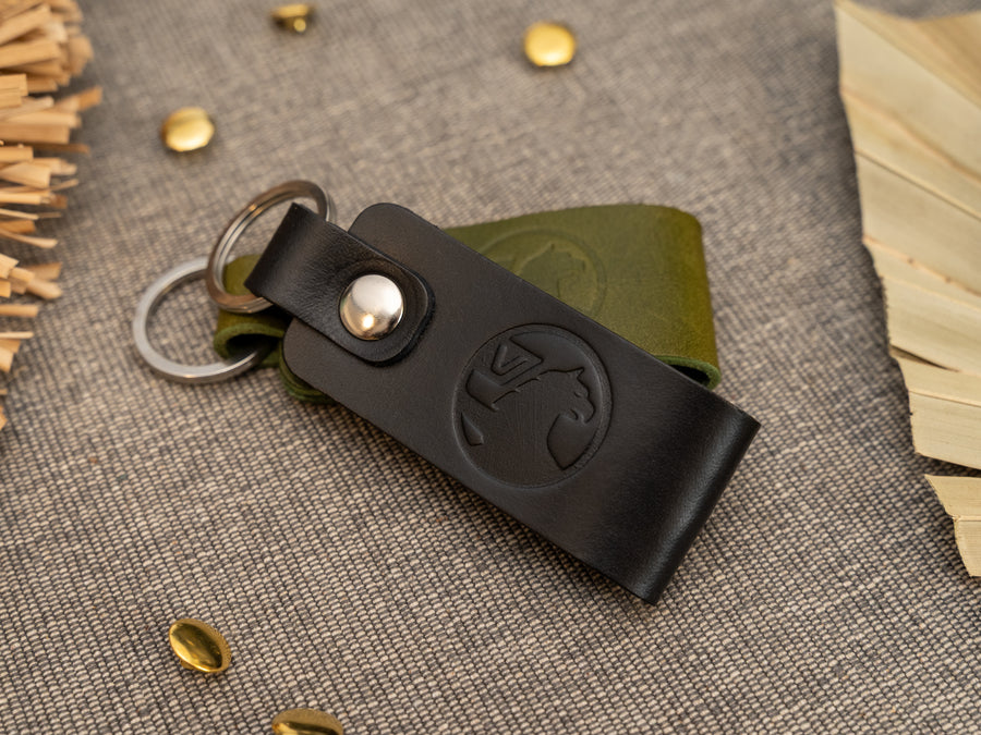 Folded black and olive green leather keyrings/keychains with the Vauxhall car logo debossed on them. Made from full grain leather with stainless steel split ring and rivet.