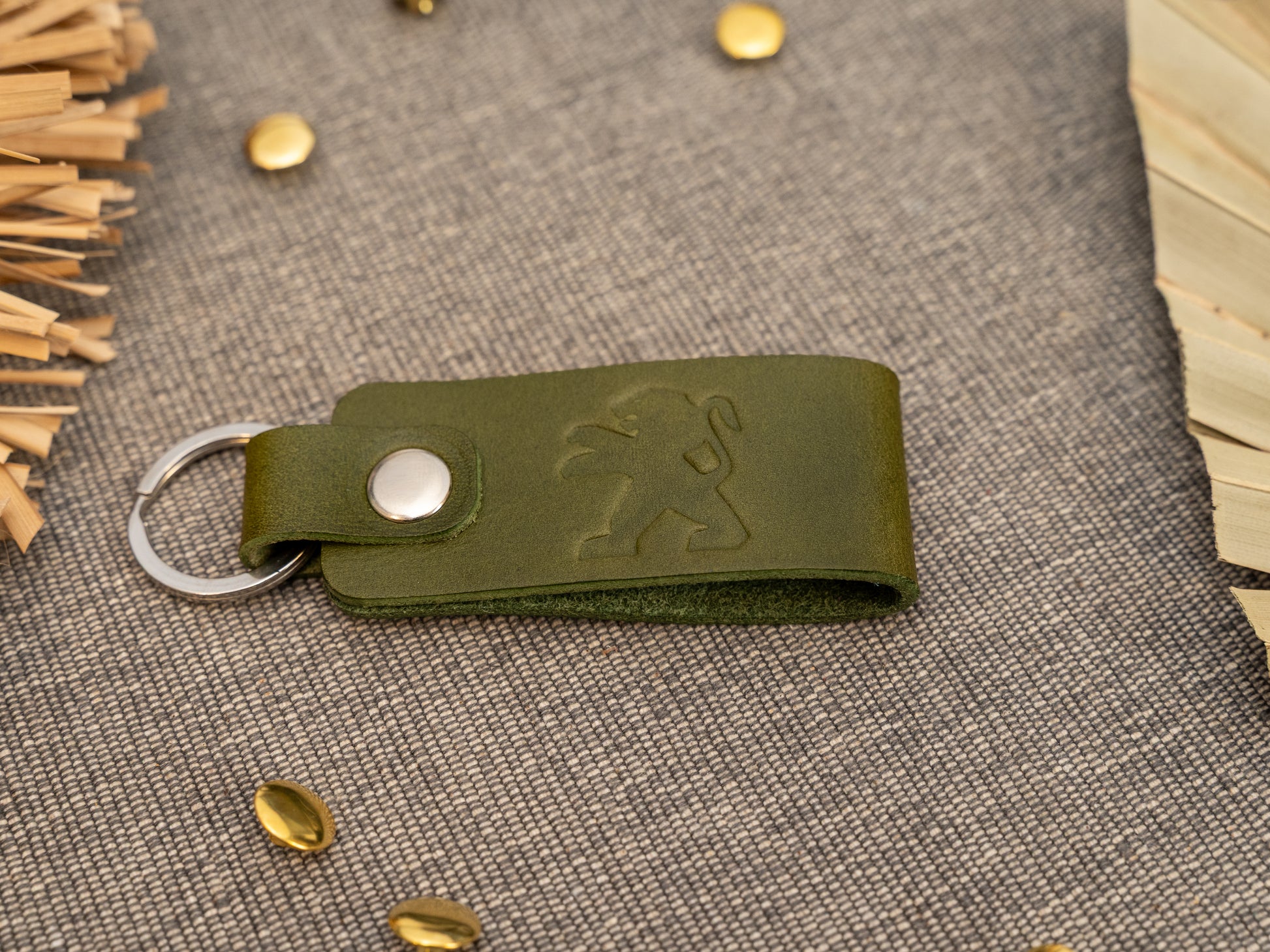 Folded olive green leather keyring/keychain with the Peugeot car logo debossed on it. Made from full grain leather.