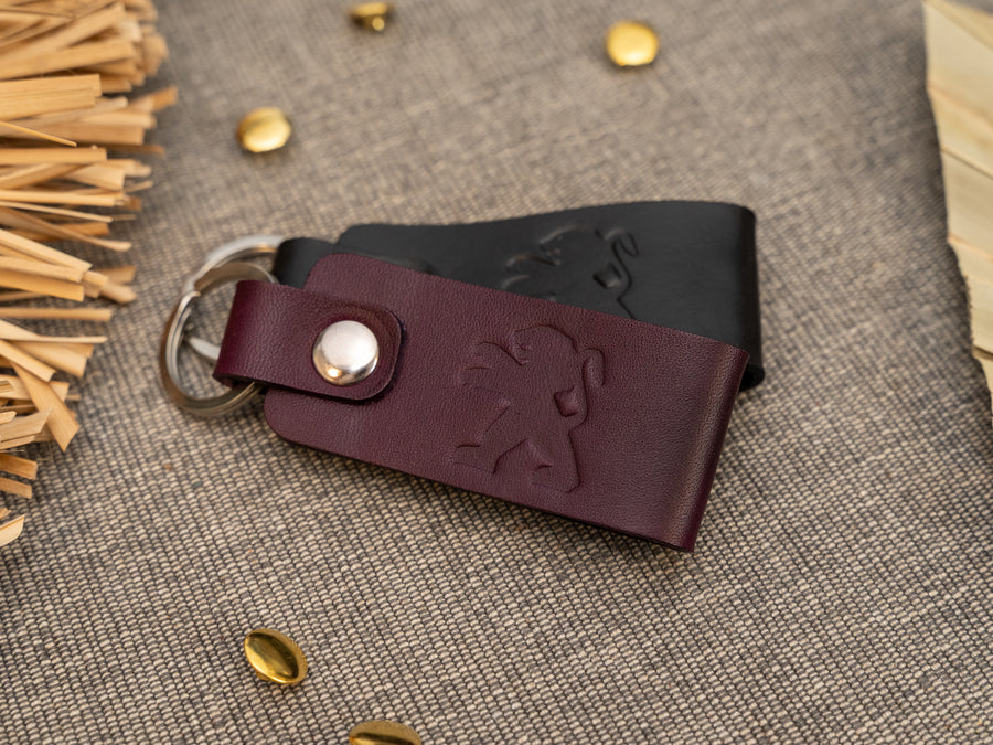 Folded purple and black leather keyrings/keychains with the Peugeot car logo debossed on them. Made from full grain leather.