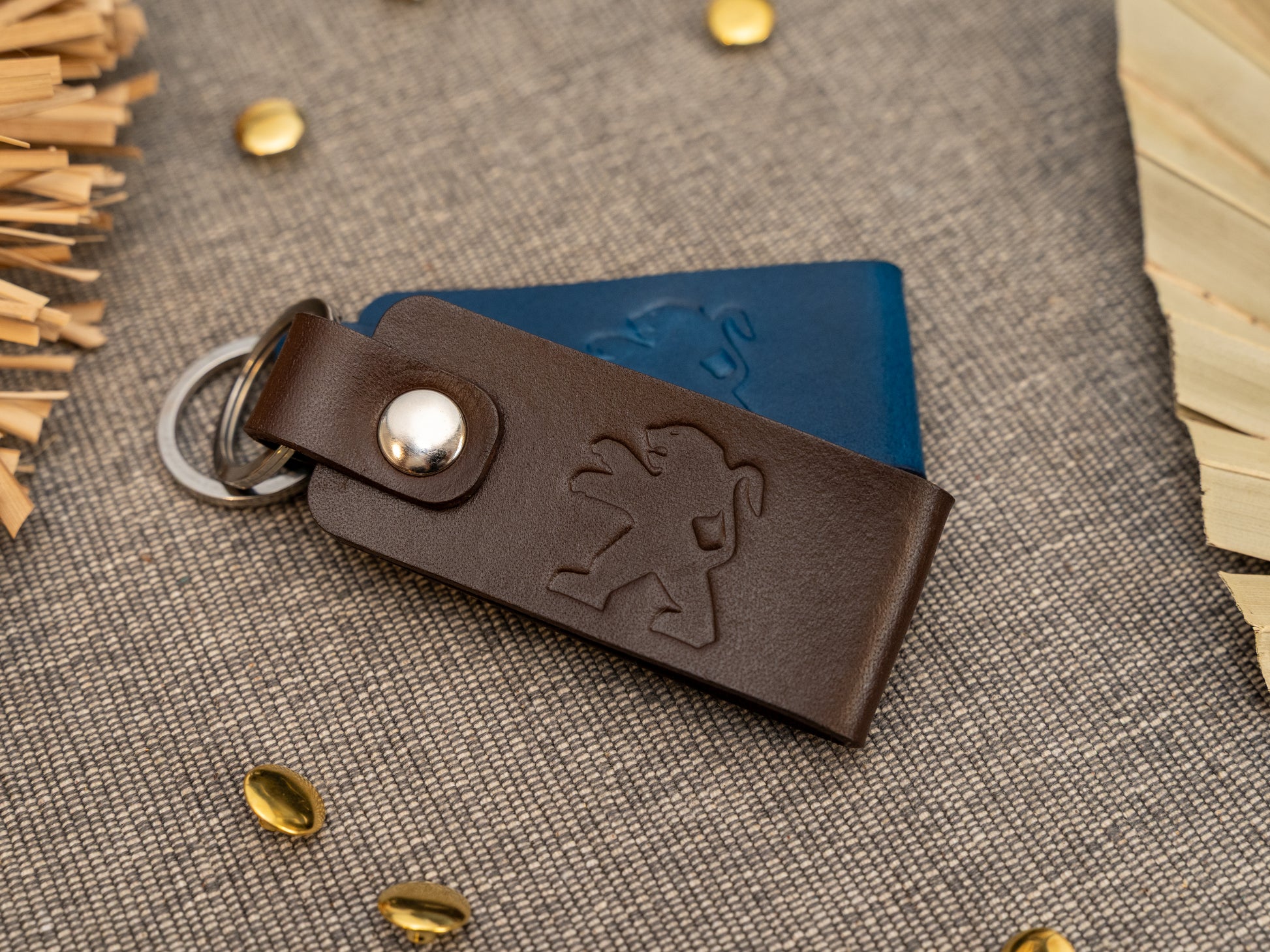 Folded dark brown and navy blue leather keyrings/keychains with the Peugeot car logo debossed on them. Made from full grain leather.
