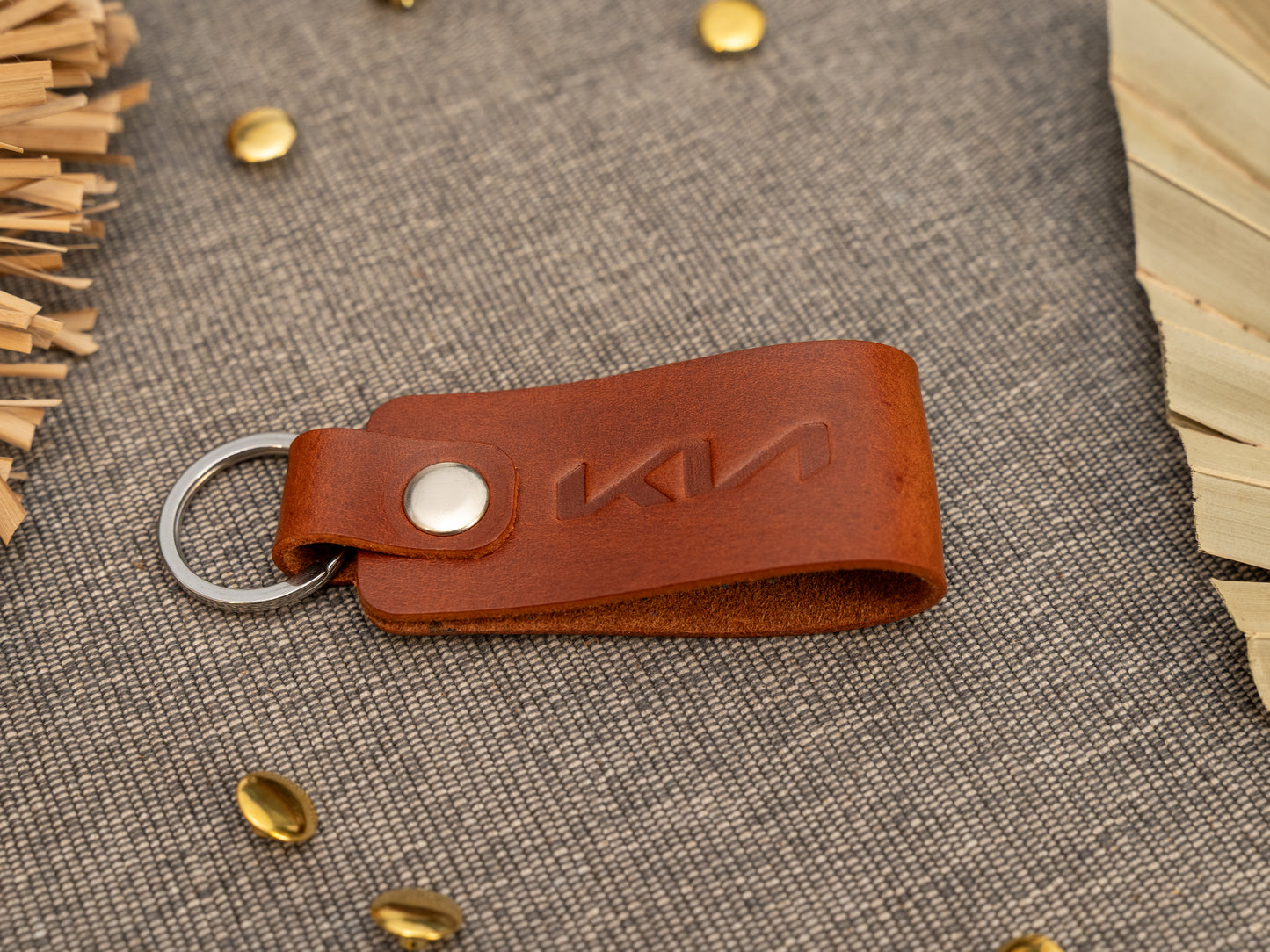 Folded tan leather keyring/keychain with the Kia car logo debossed on it. Made from full grain leather with stainless steel split ring and rivet.