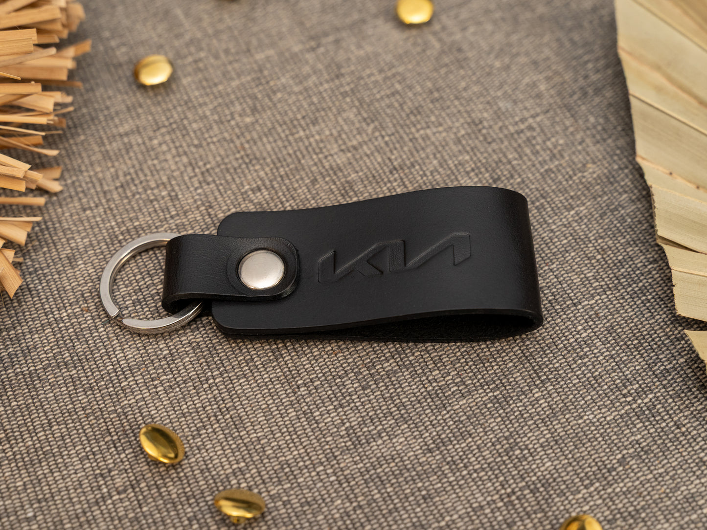Folded black leather keyring/keychain with the Kia car logo debossed on them. Made from full grain leather with stainless steel split ring and rivet.