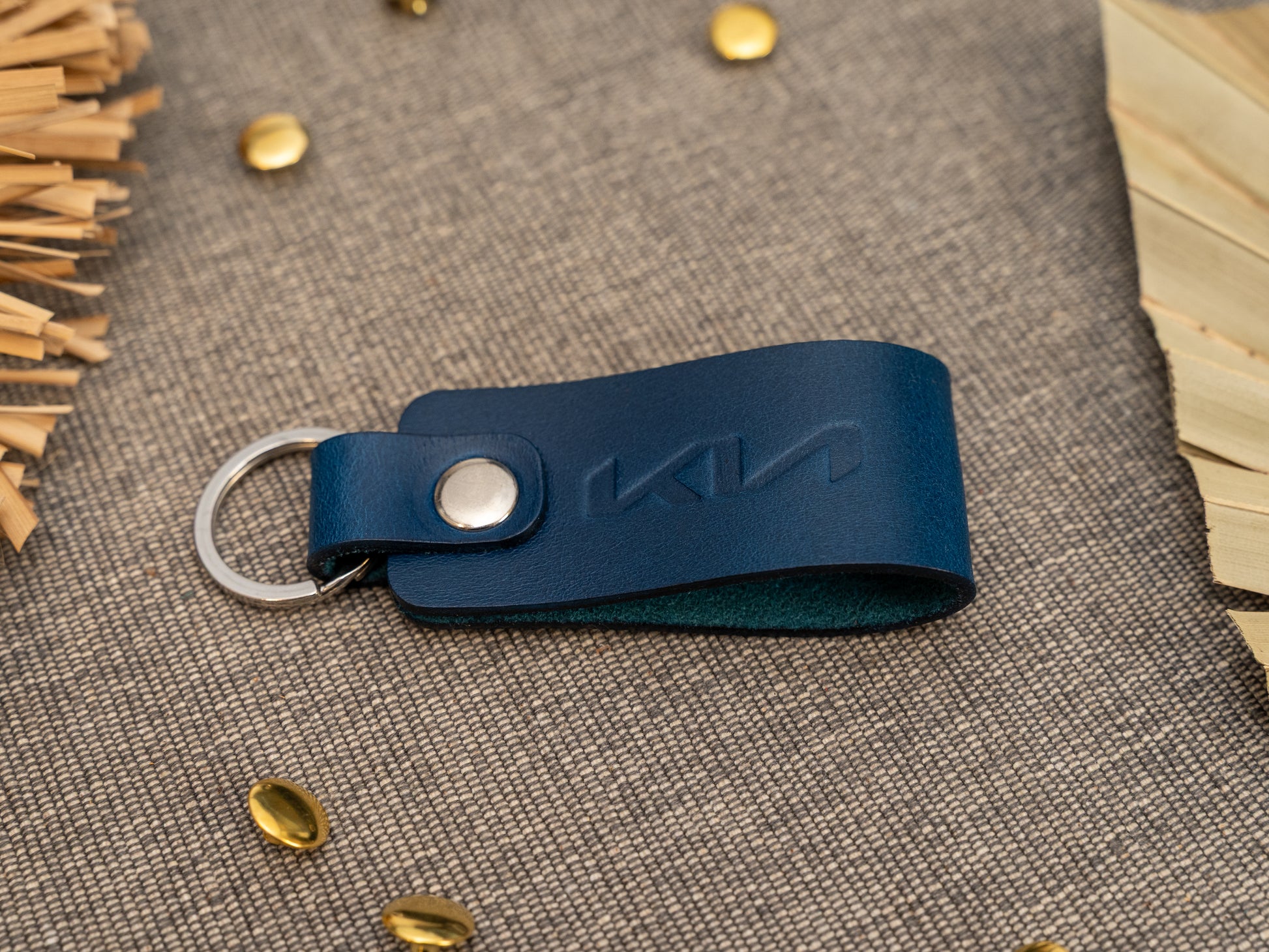 Folded navy blue leather keyring/keychain with the Kia car logo debossed on it. Made from full grain leather with stainless steel split ring and rivet.