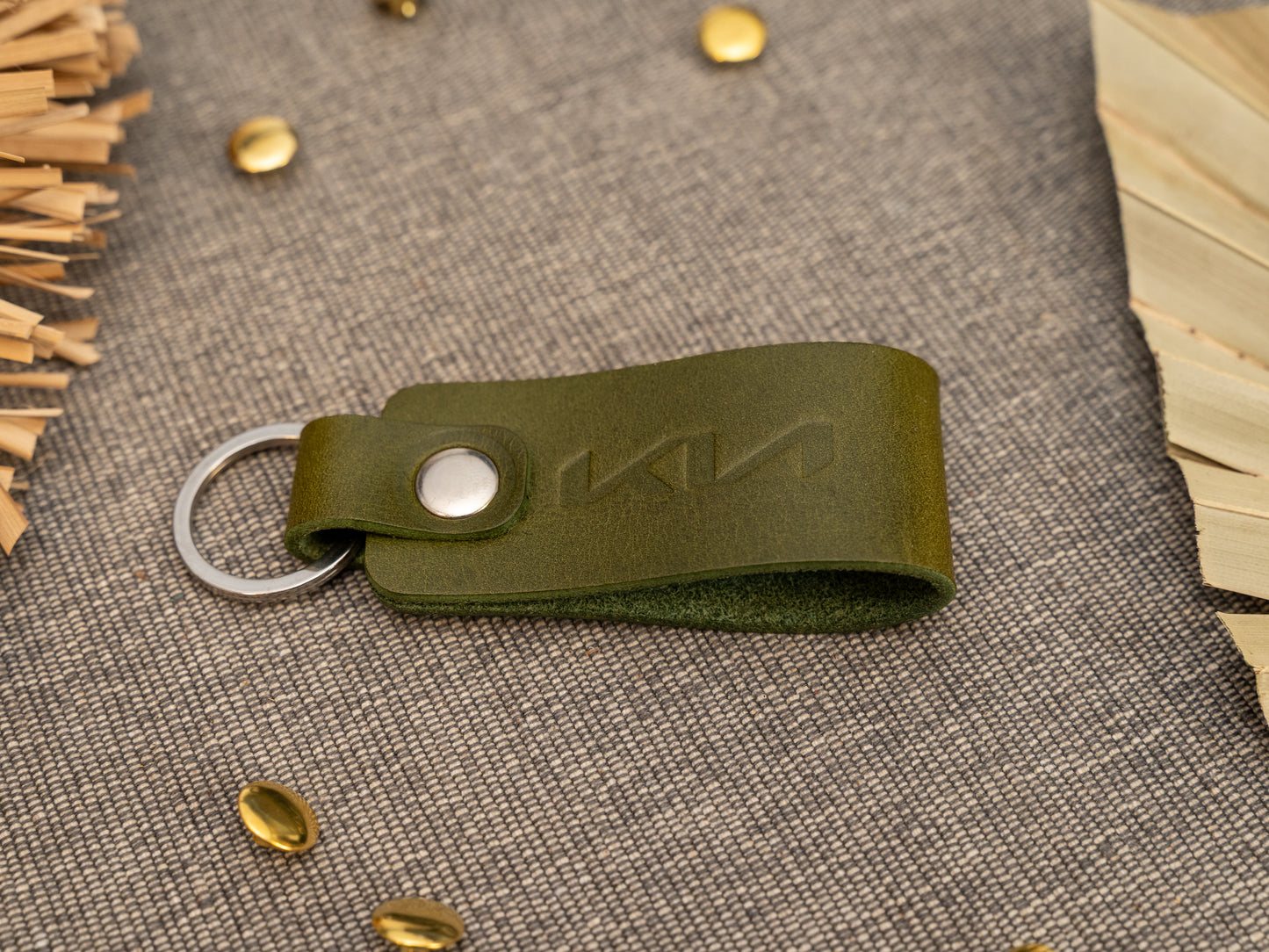 Folded olive green leather keyring/keychain with the Kia car logo debossed on it. Made from full grain leather with stainless steel split ring and rivet.