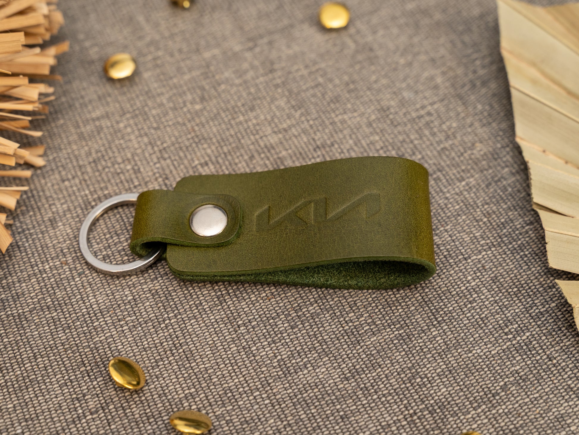 Folded olive green leather keyring/keychain with the Kia car logo debossed on it. Made from full grain leather with stainless steel split ring and rivet.