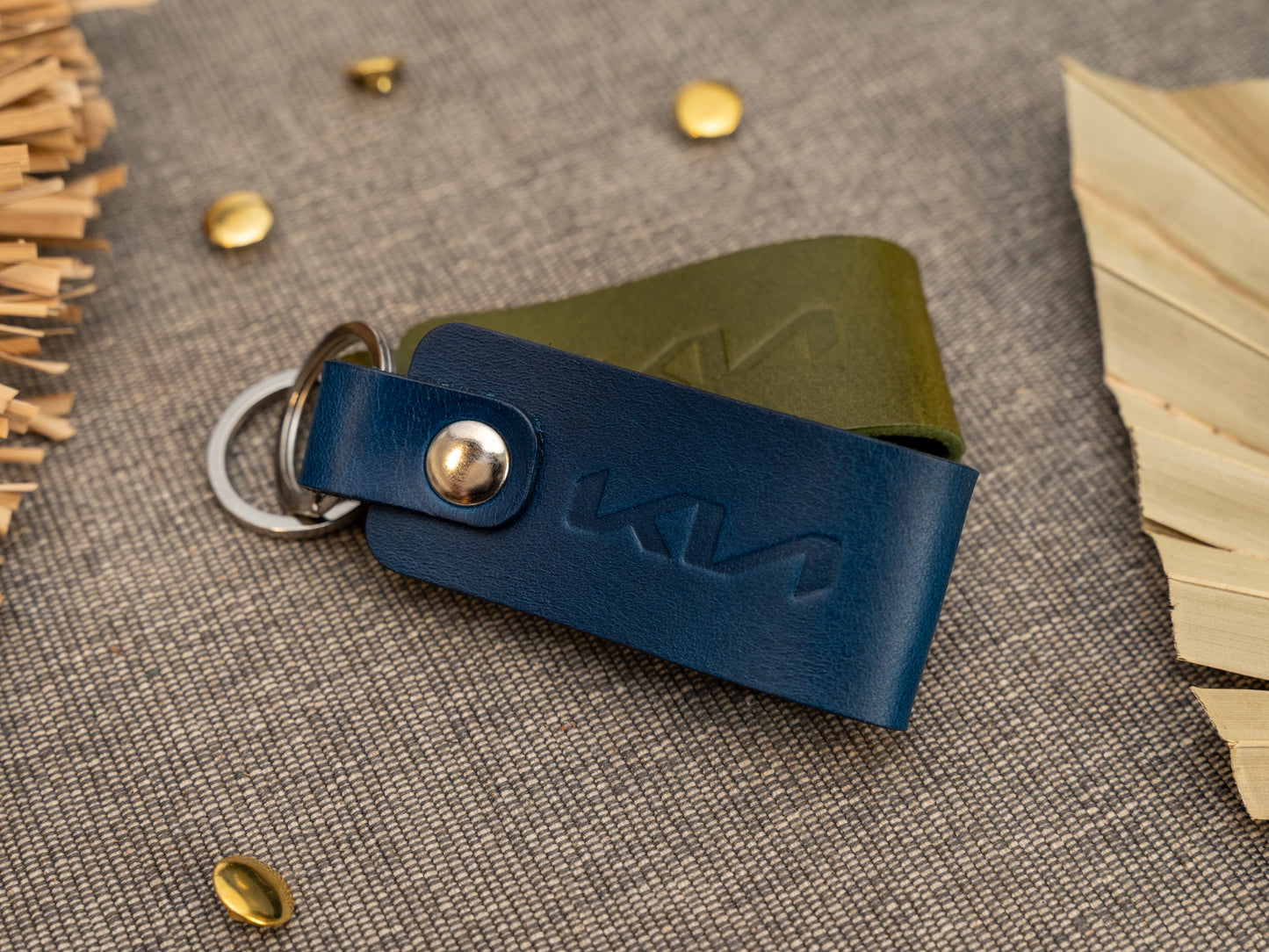 Folded navy blue leather keyrings/keychains with the Kia car logo debossed on them. Made from full grain leather with stainless steel split ring and rivet.