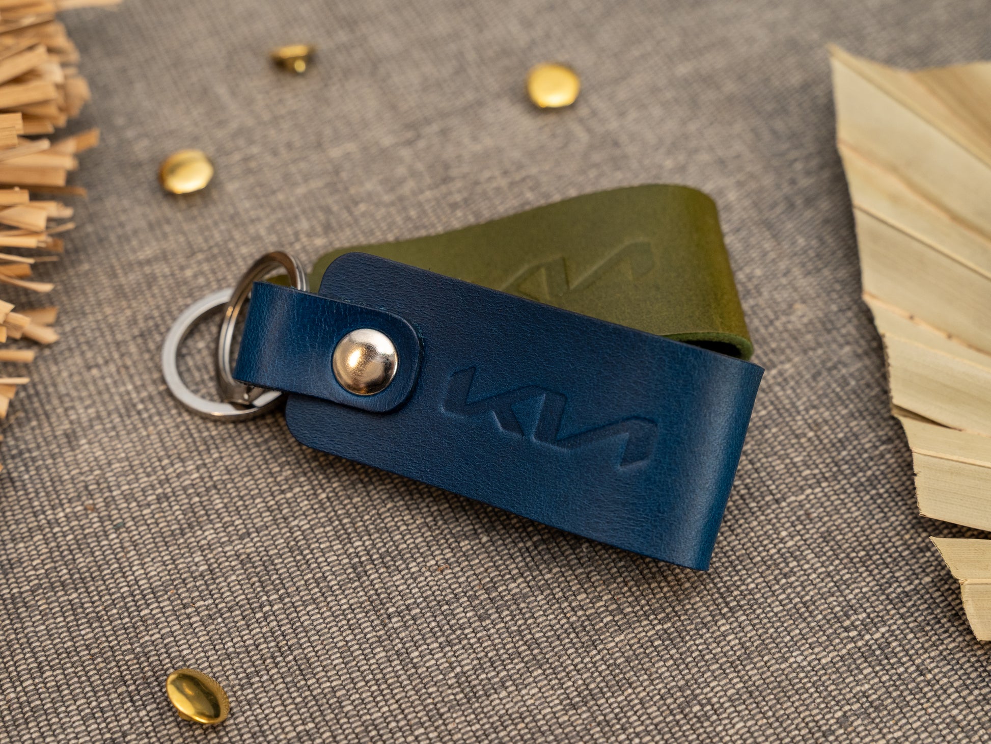 Folded navy blue leather keyrings/keychains with the Kia car logo debossed on them. Made from full grain leather with stainless steel split ring and rivet.