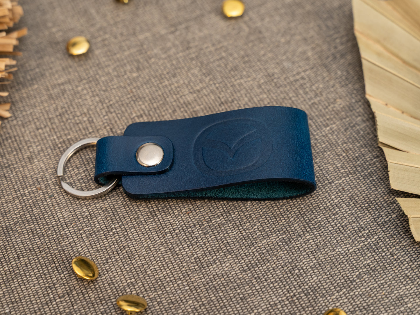 Folded navy blue leather keyring/keychain with the Mazda car logo debossed on it. Made from full grain leather with stainless steel split ring and rivet.