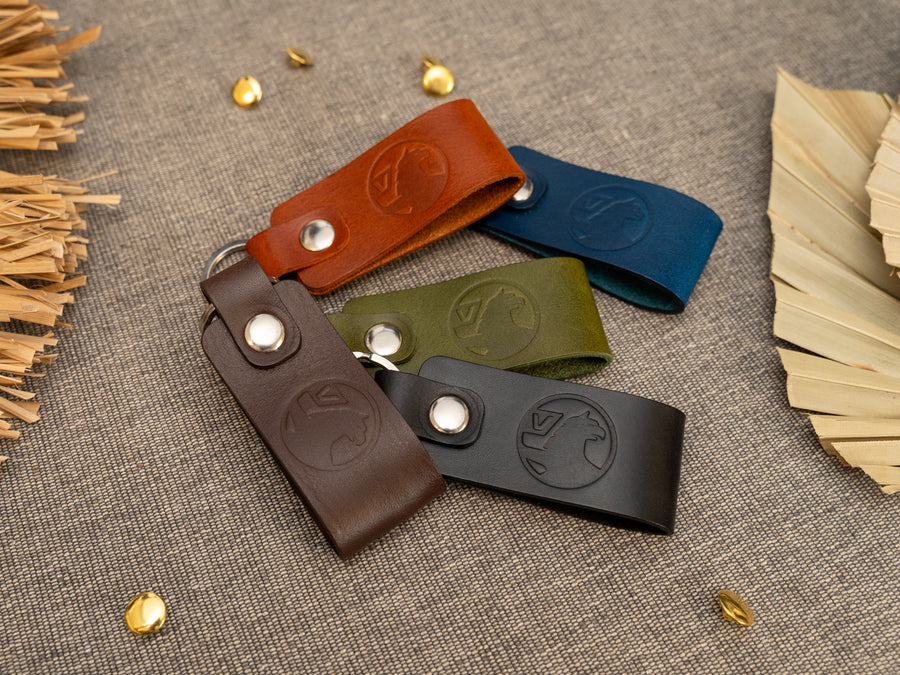 Several keyrings with a folded design in various colours such as tan, olive green, navy blue, dark brown and black keyrings/keychains embossed with the Vauxhall car logo. Stainless steel split ring and rivet.