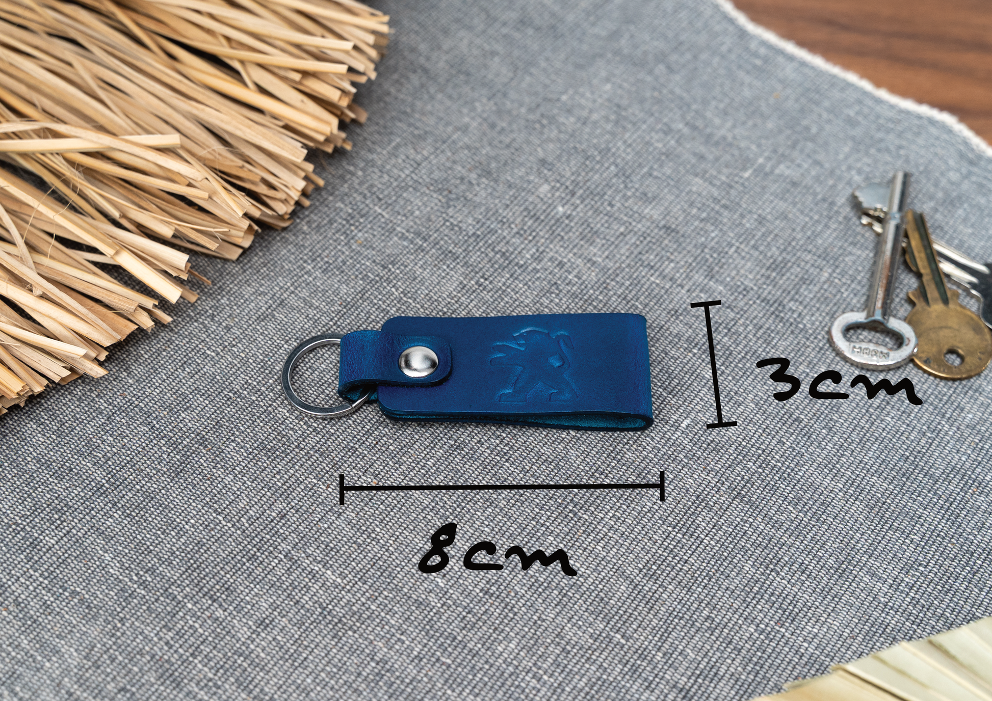 Folded navy blue leather keyring with the Peugeot car logo debossed on it. Measuring 8cm by 3cm. Made from Italian full grain leather