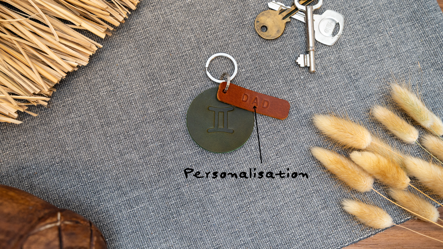 Round olive green keyring embossed with name showing personalisation. Stainless steel split ring and rivet.